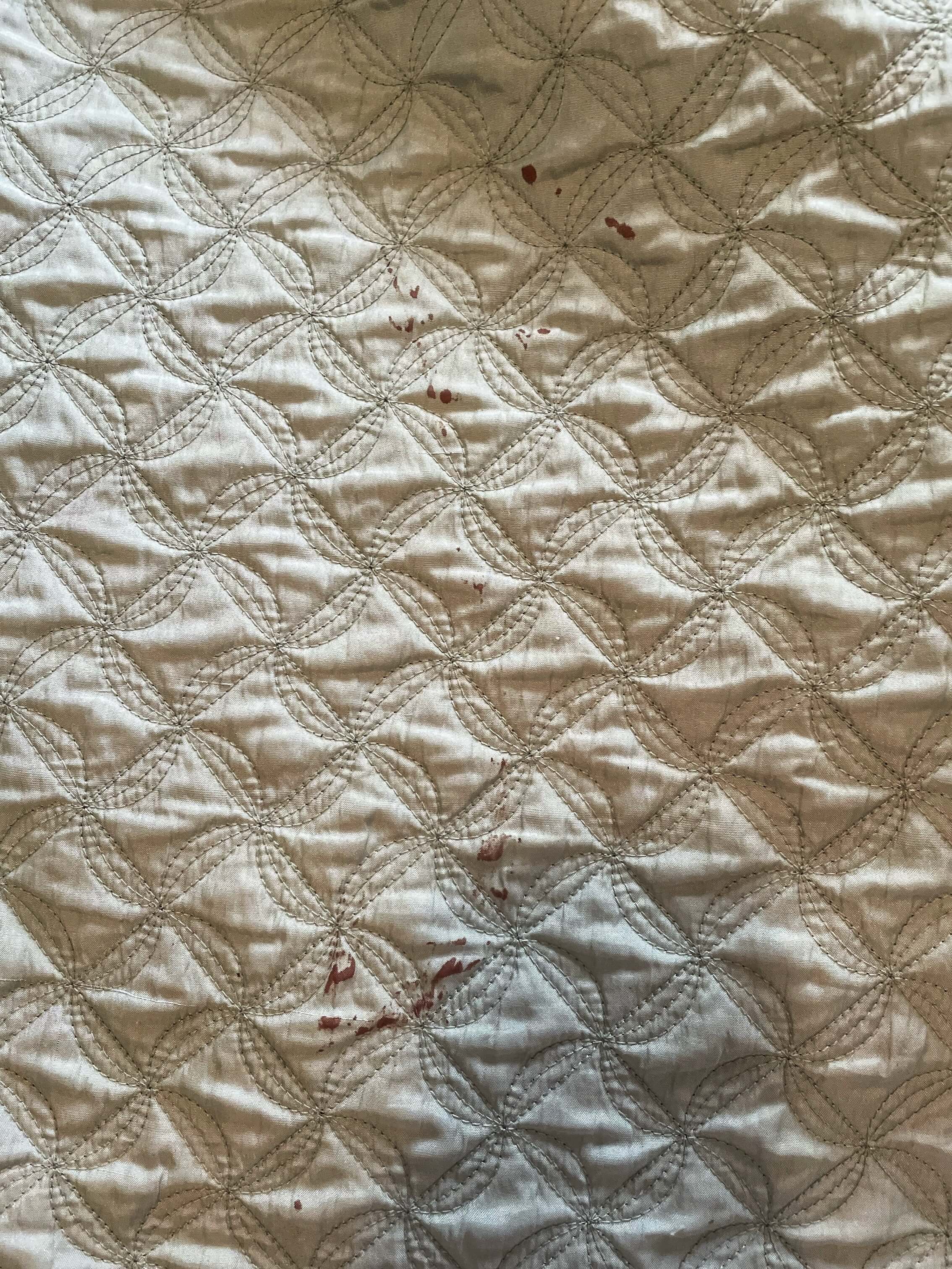 Blood stains on a white quilt.