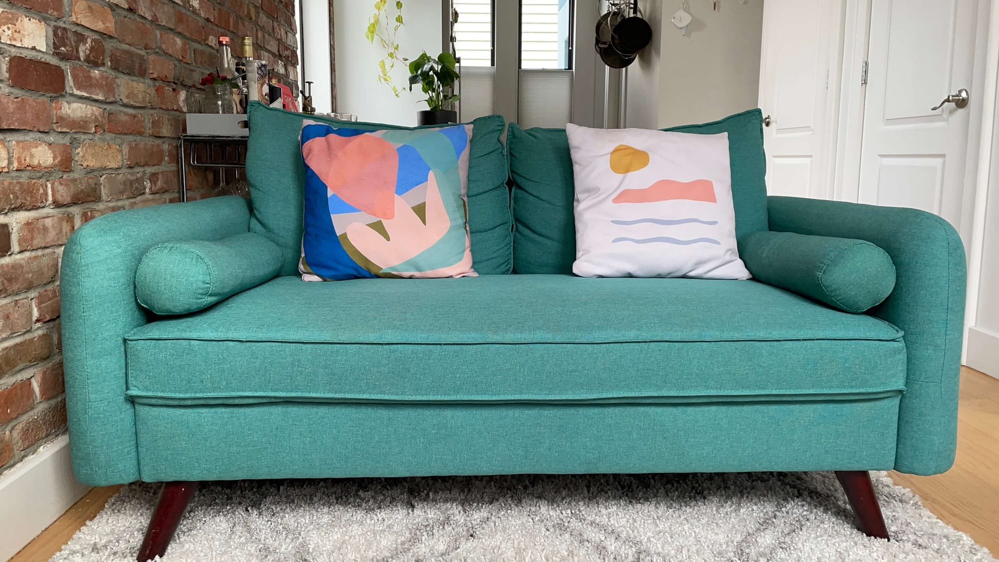 A bright teal couch with artsy pillows.