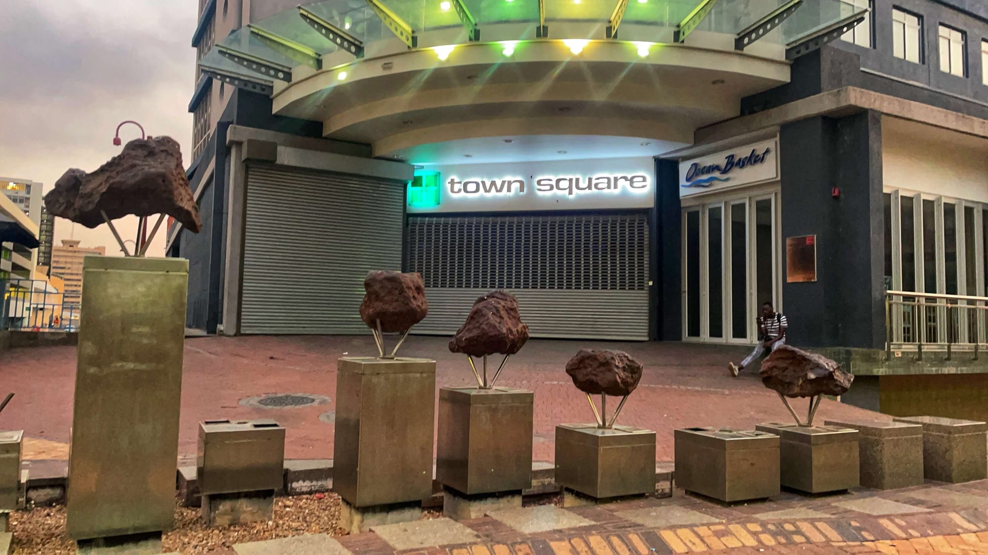 An installation of meteorites the size of soccer balls along a public sidewalk.