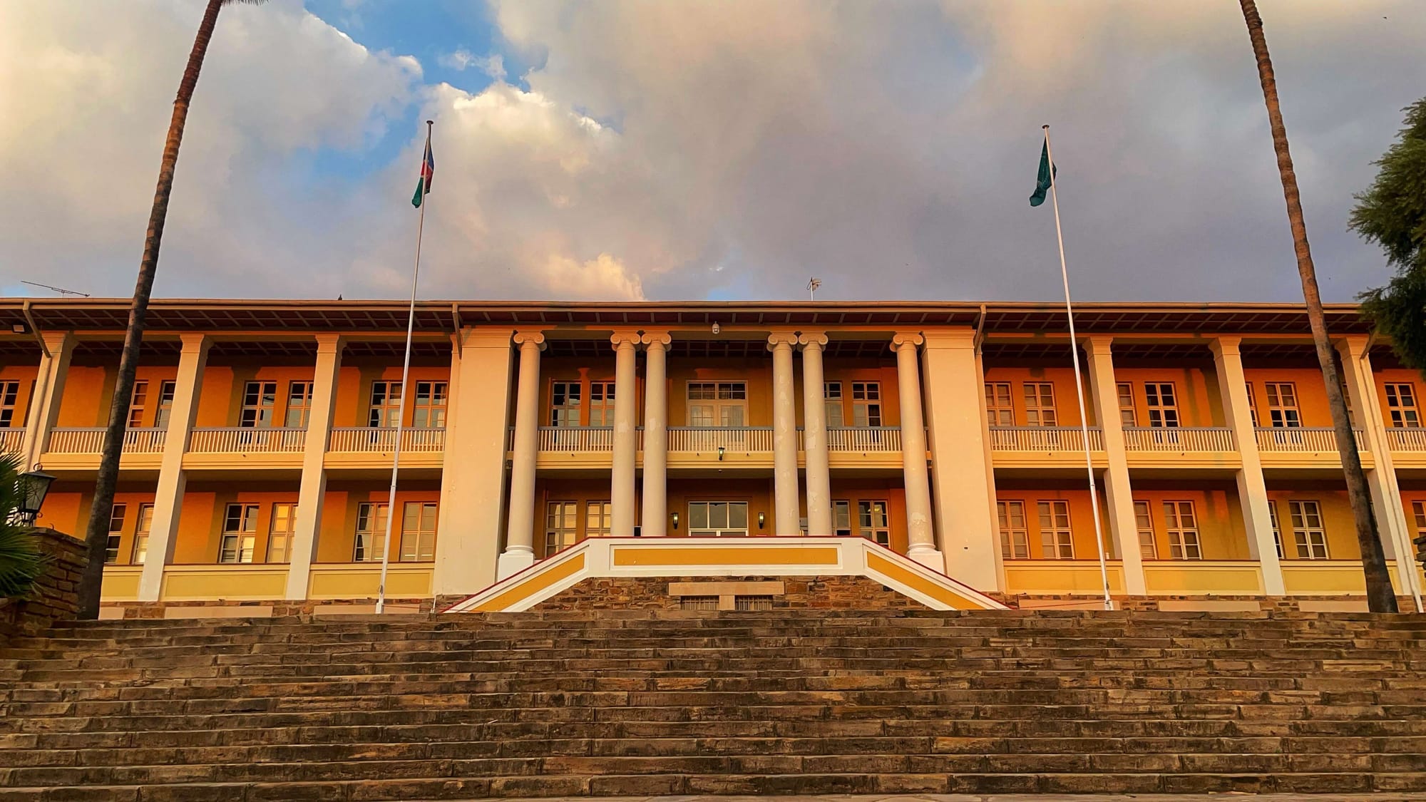 A golden glow cast over a two-story building with columns that sits at the top of tall steps.