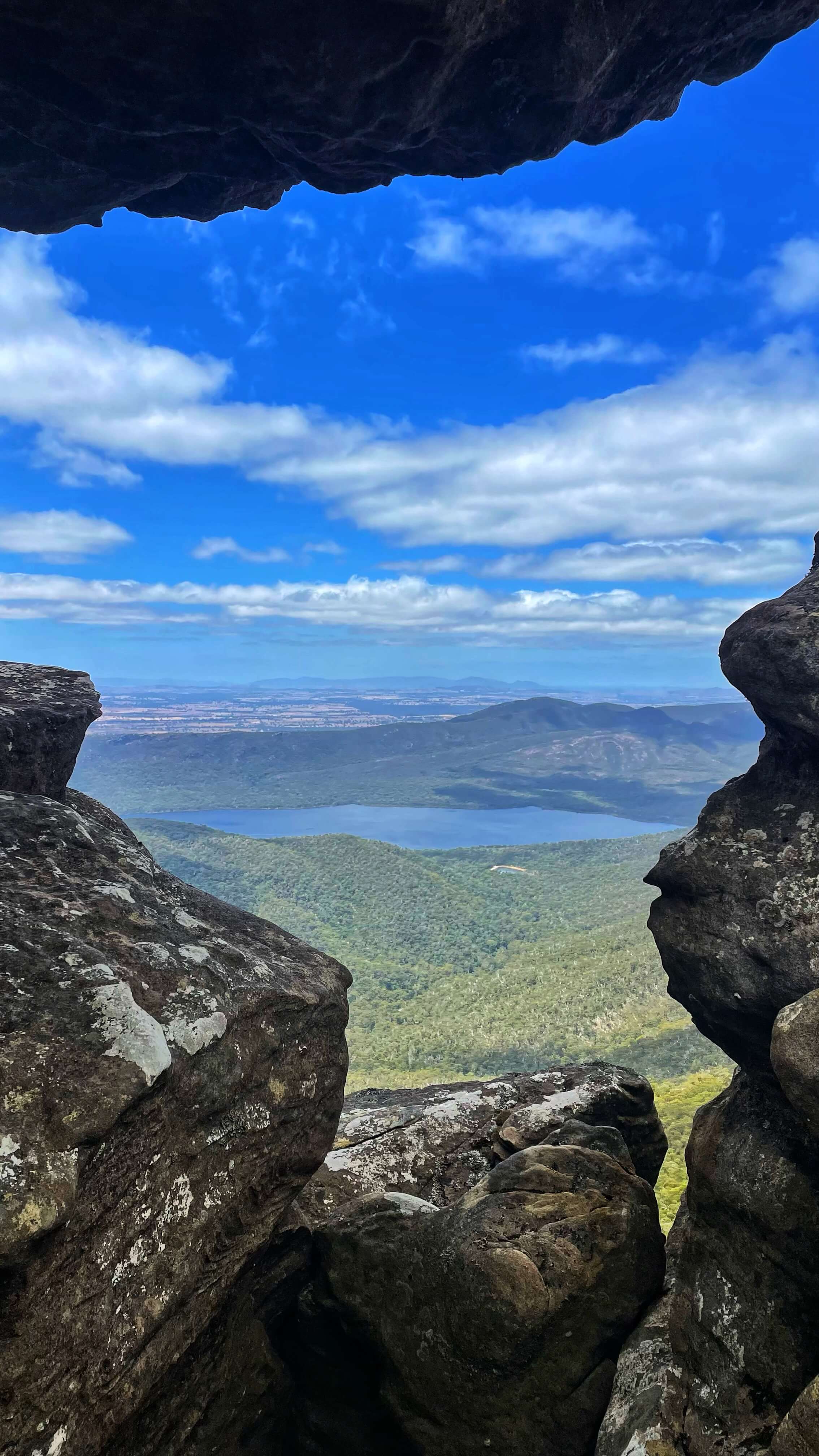 Peeking out between rocks from elevation, down in the valley below, a big blue lake.