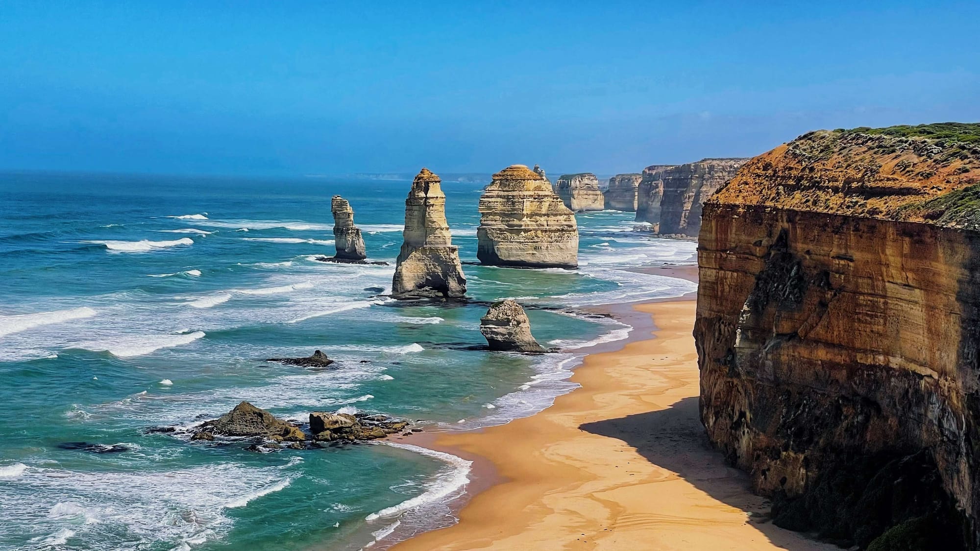 Tall limestone stacks tower above the ocean along the coast.