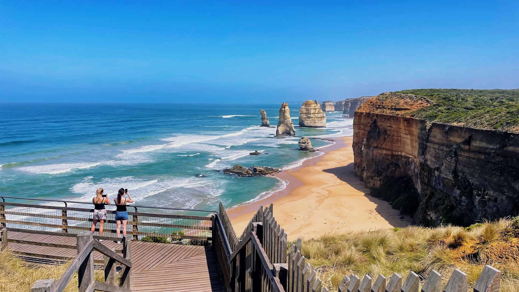 Two women take pictures of the unique limestone formations from a viewing platform on the cliffside.