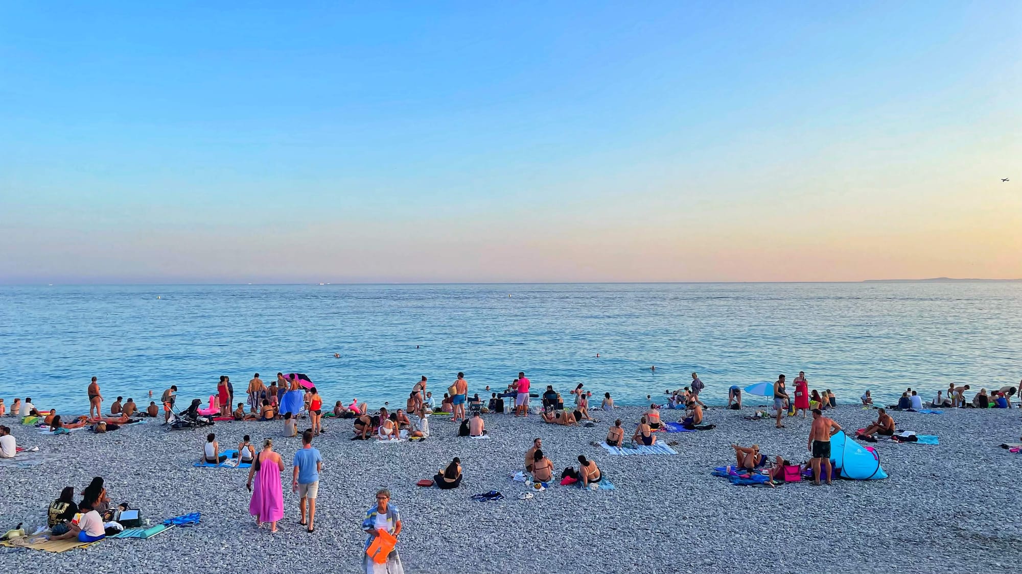 A crowded beachfront at sunset in Nice, France.