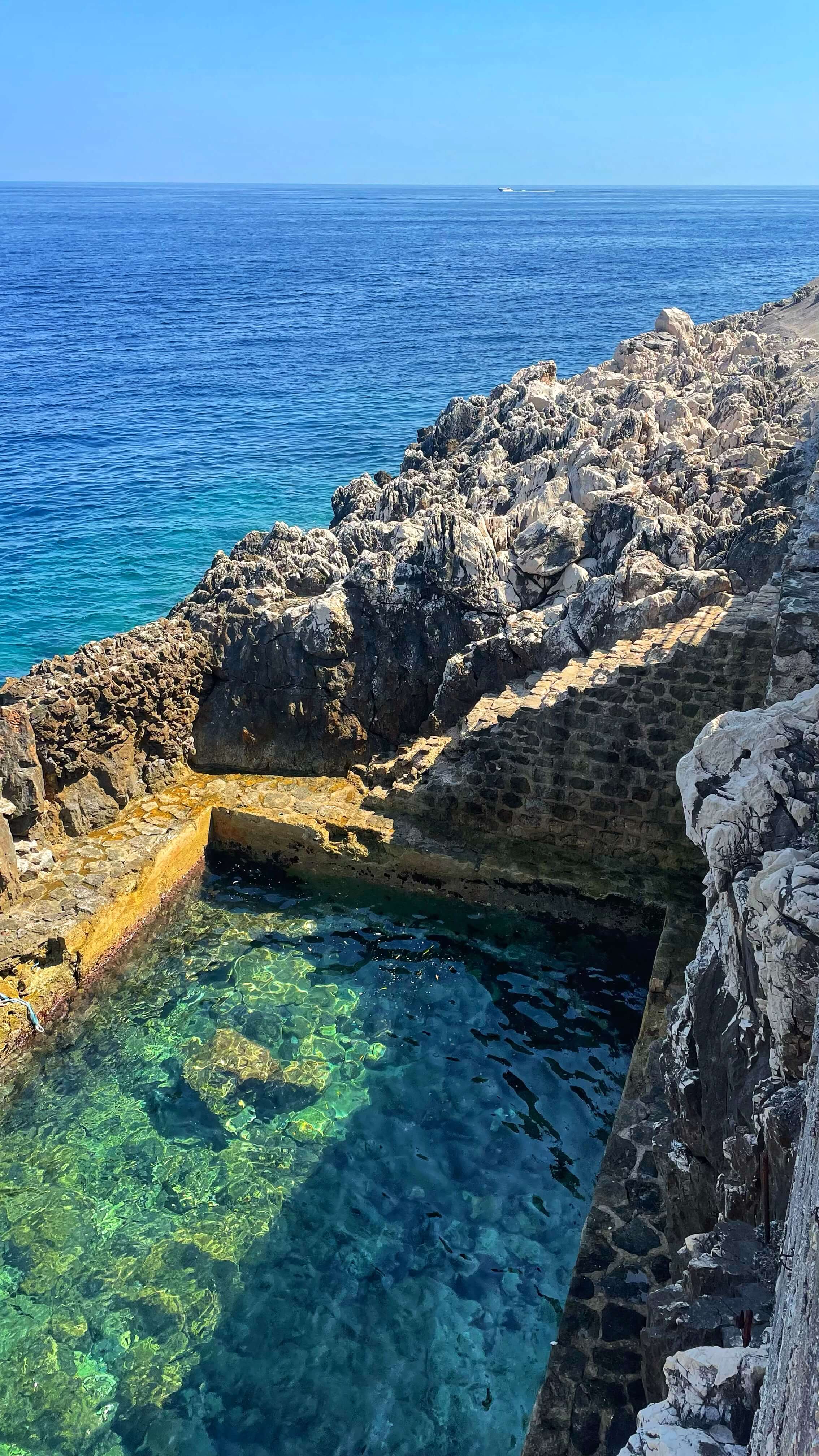 A rectangular ocean pool and boat docking area along the rocks of the Cap Ferrat coastline.