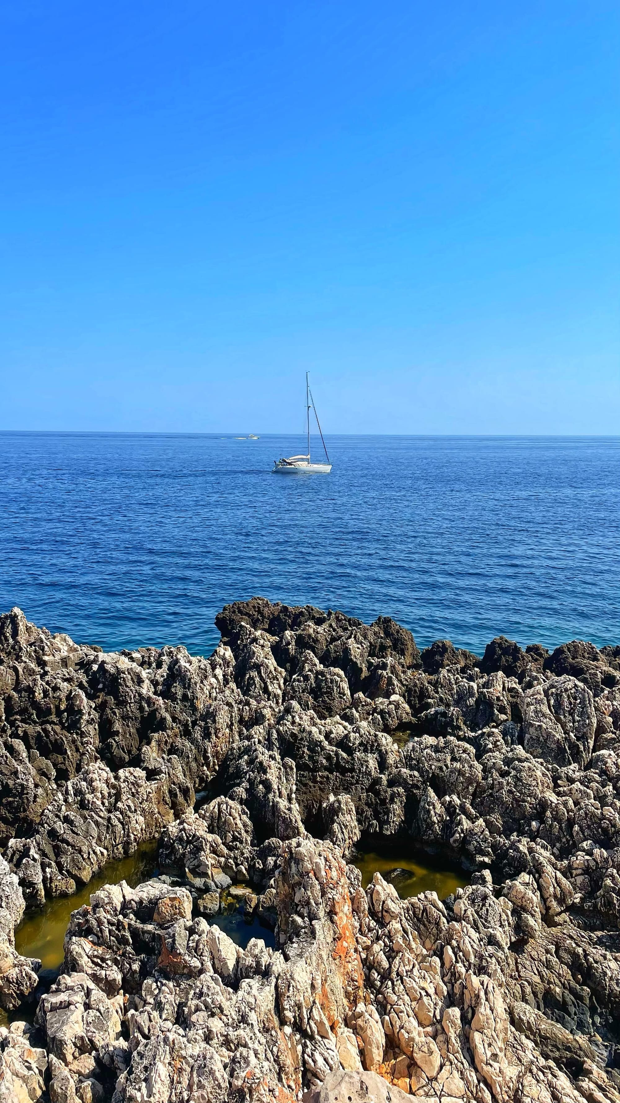 A sailboat in the ocean off of Pointe Malongue, on the Cap Ferrat trail.