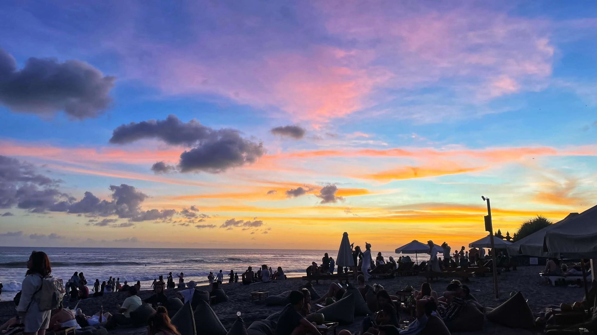 The end of sunset on a busy beach, with dark blue, pink and orange on the horizon.