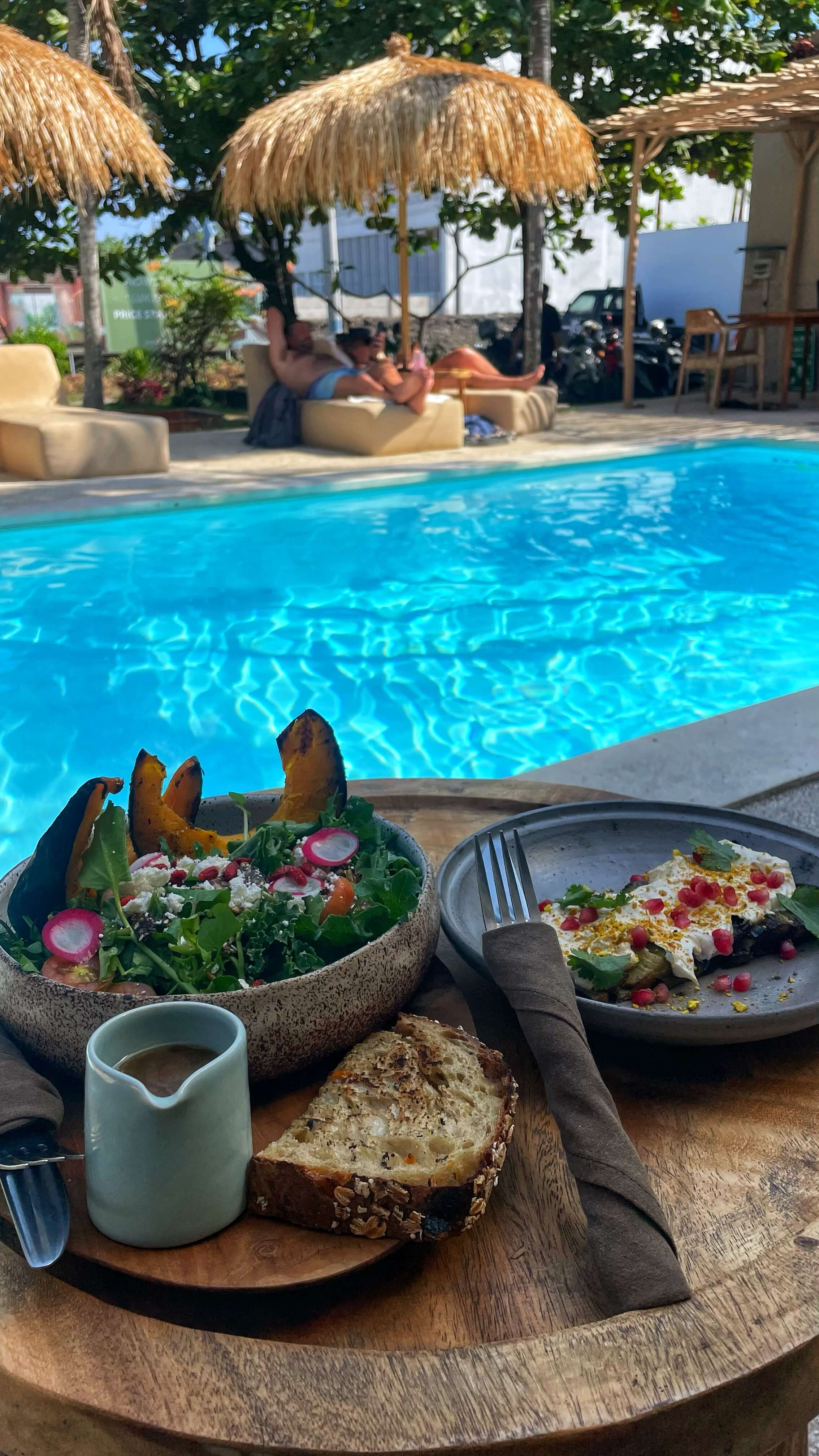 An acorn squash and green salad, along with aubergine labneh toast, poolside.