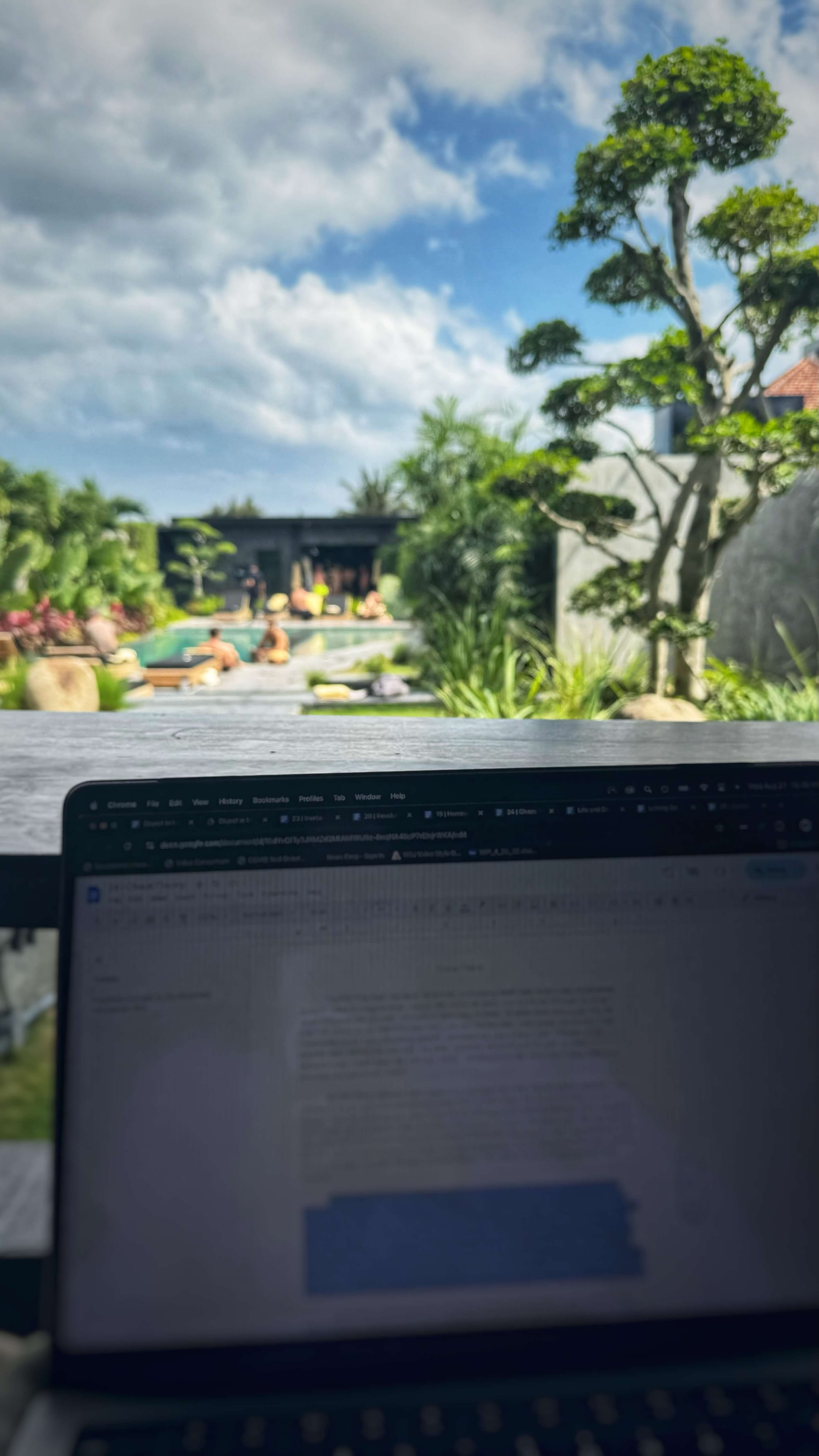 A laptop with a view of a tropical pool area in the background.