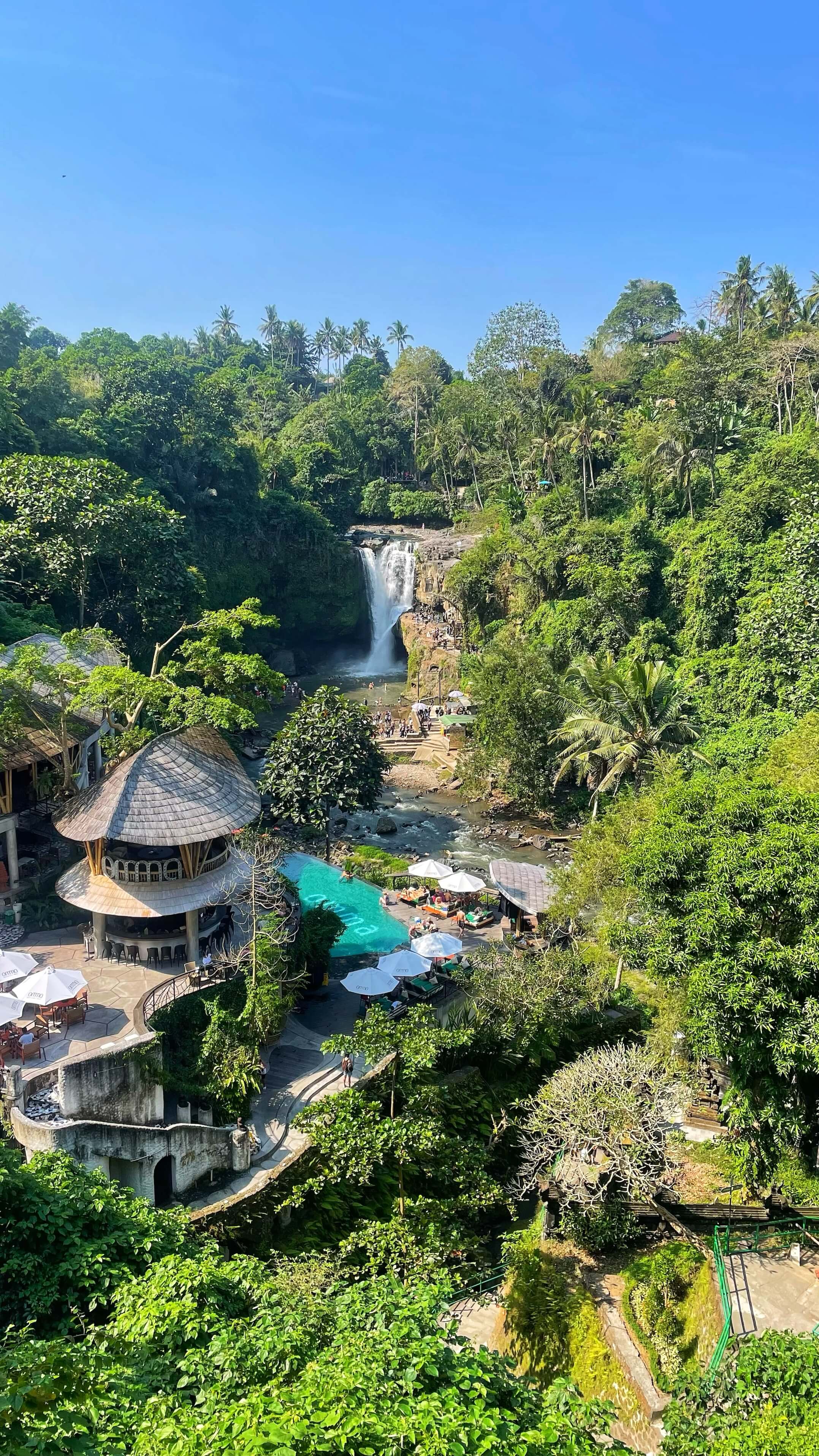 A waterfall surrounded by jungle and multi-story clubs with pools. 