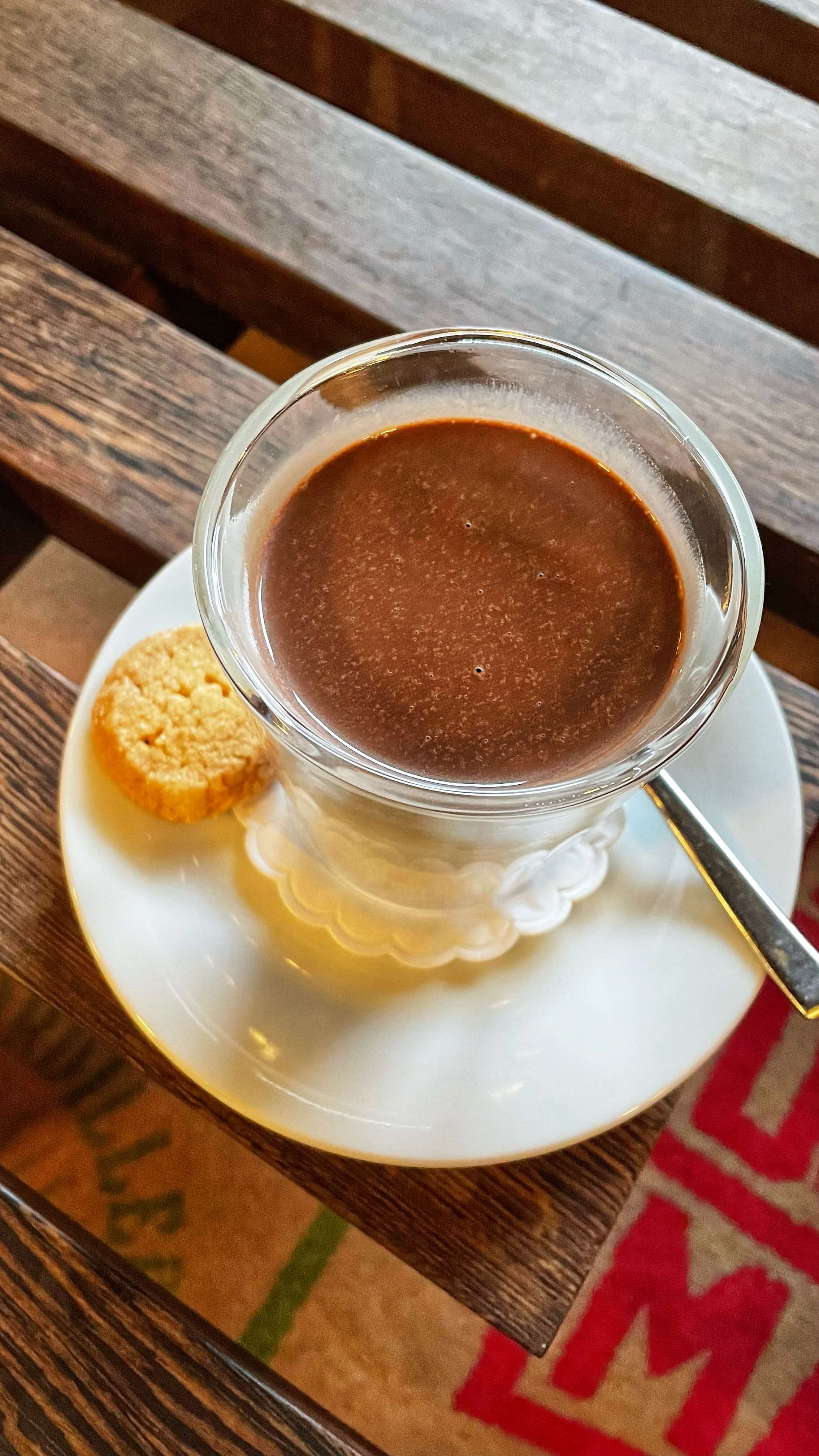A small cup of hot chocolate and a biscuit.