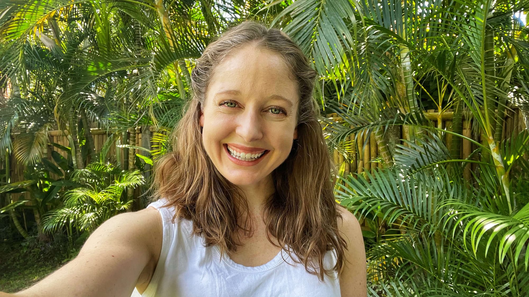 Clara Ritger, author of Adventure to Awaken, smiling at the camera, with the Bali jungle in the background.