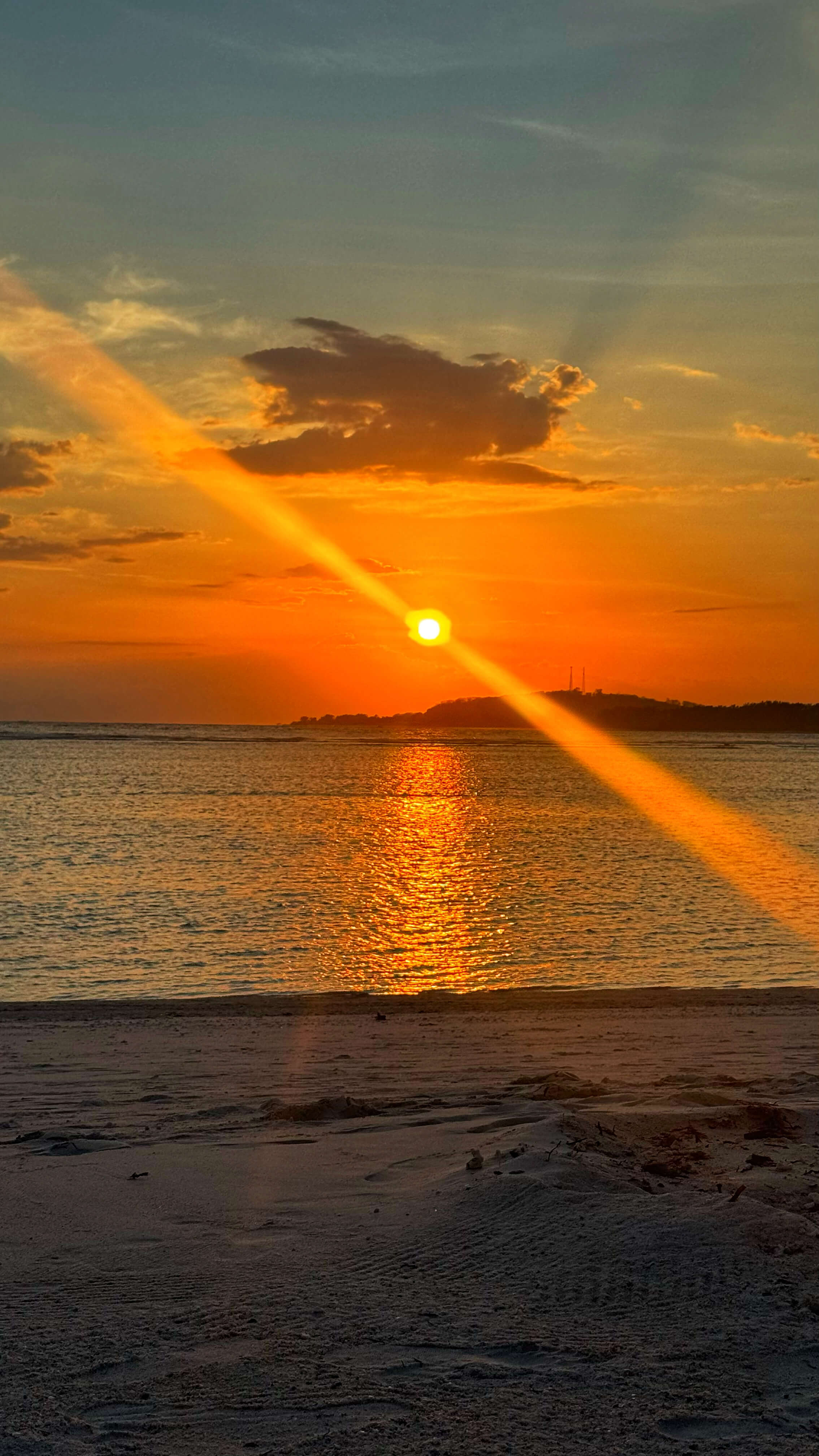 An orange sun with a diagonal ray of light streaking out of it, like a lighthouse.