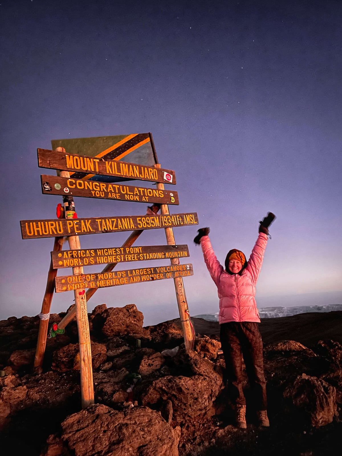 Clara Ritger throws her hands in the air to celebrate at the summit of Mount Kilimanjaro in Tanzania, Africa, before sunrise.