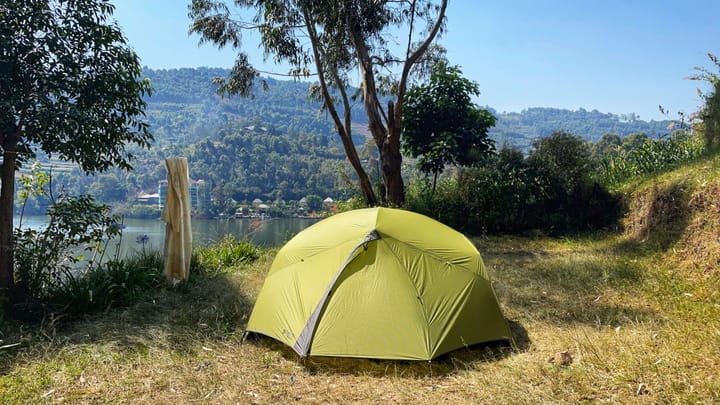 A green tent on grass overlooking a l