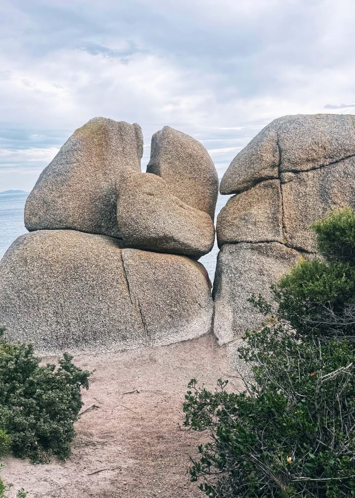 A picture of large boulders along the coast, cracked down the middle. 